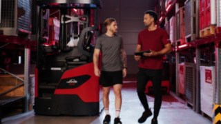 Linde reach forklifti Ri16 önünde spor kıyafetli, biri tablet tutan iki kişi.